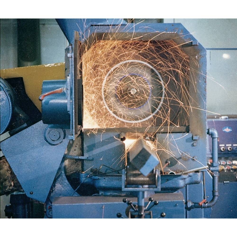 Przemysłowa maszyna z otwartą obudową, w której lecą iskry podczas obróbki elementu metalowego.