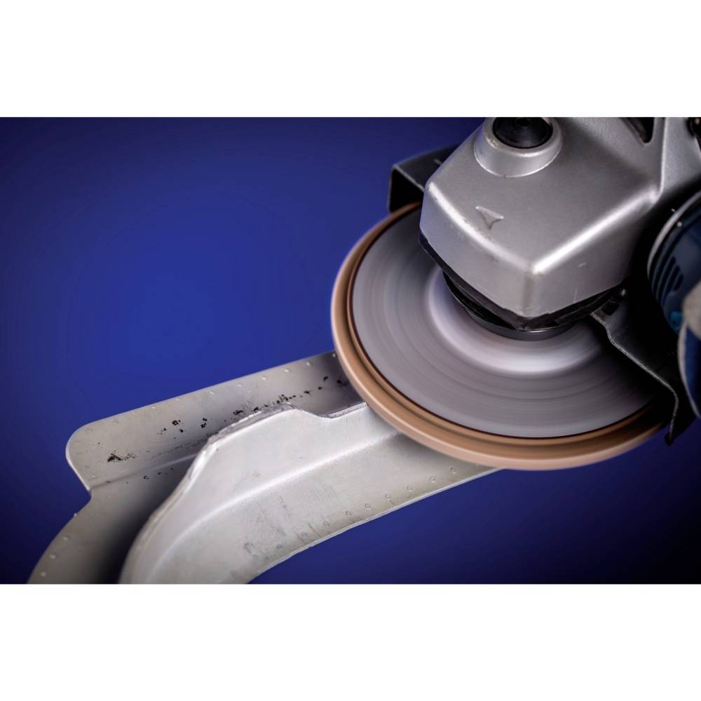 Szlifierka obrabia krawędź metalu, iskry lekko tryskają. Scena przedstawia przemysłową obróbkę metalu w zbliżeniu.