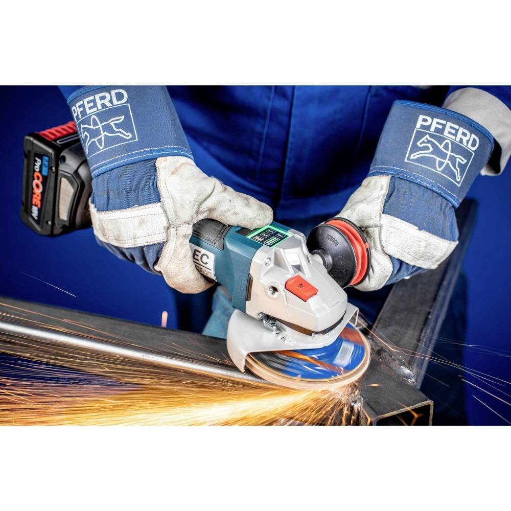 Robotnik używa szlifierki kątowej, lecą iskry. Nosić rękawice ochronne i odzież roboczą. Obróbka metalu w środowisku warsztatu.