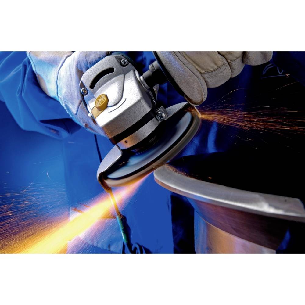 Osoba w odzieży ochronnej pracuje z szlifierką kątową, z której tryskają iskry. Główny nacisk położony jest na obróbkę metalu.