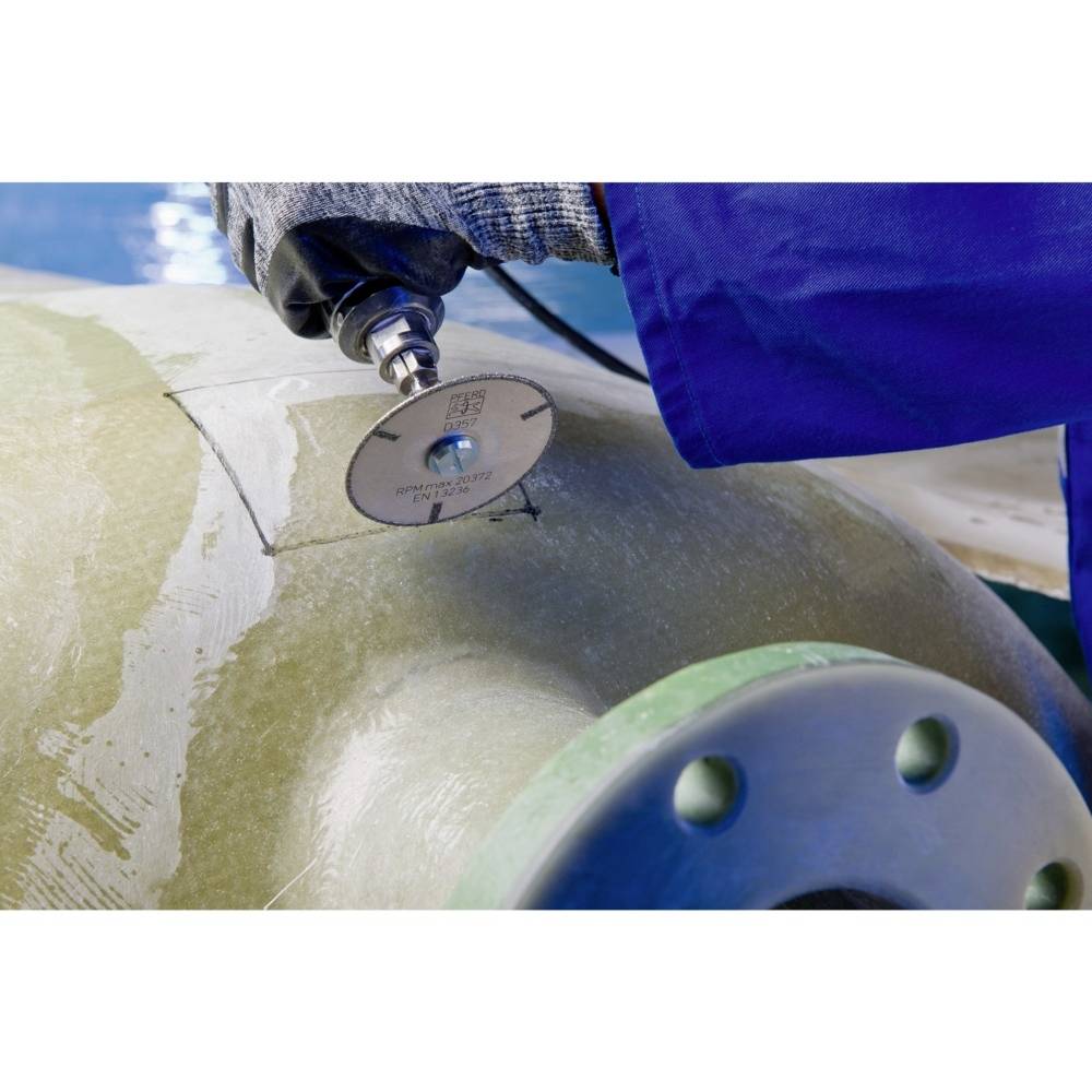 Robotnik ucina rurę jasnymi cięciami za pomocą szlifierki kątowej. Skupienie jest na samym procesie cięcia.