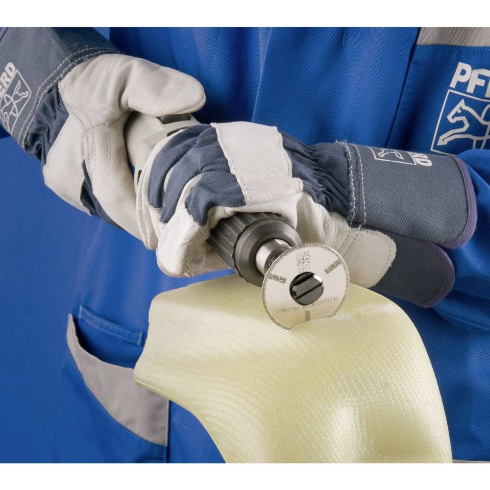 Osoba w odzieży ochronnej trzyma narzędzie obrabiające matę z włókna szklanego. Ręce są w rękawicach ochronnych.