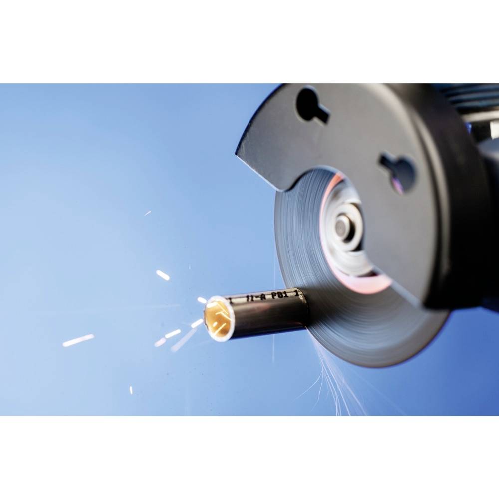 Metalowy pręt jest cięty obracającą się tarczą tnącą, iskry tryskają. Tło w kolorze niebieskim, fokus na tarczy i rurze.