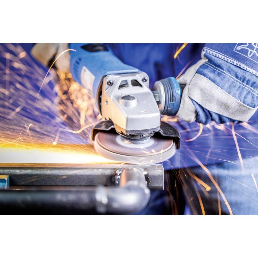 Robotnik szlifuje metal szlifierką kątową, a wokół lecą iskry. Widoczne są ubranie ochronne i rękawice, które są ważne dla bezpieczeństwa.