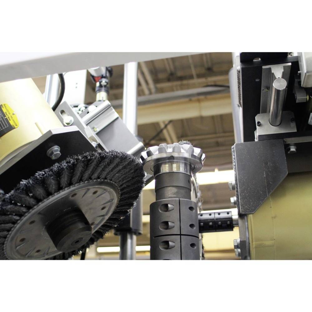 Przemysłowe narzędzie do szlifowania i polerowania obrabia metalowy element zębaty w środowisku fabrycznym.