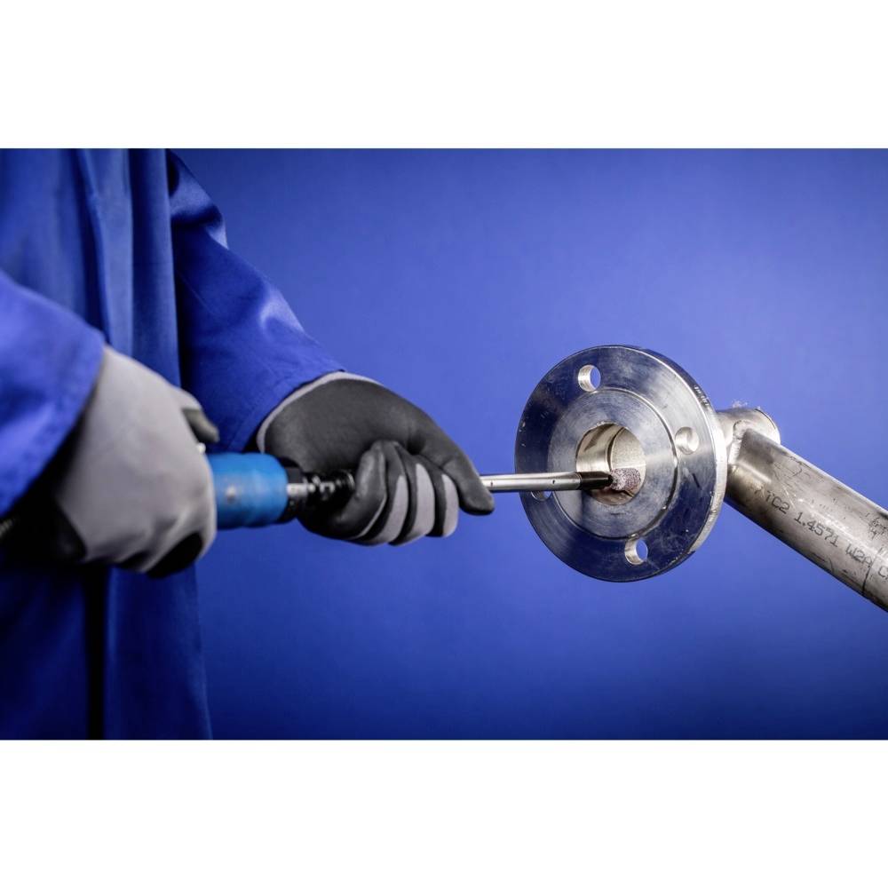 Osoba w niebieskim stroju ochronnym używa narzędzia do pracy przy połączeniu metalowym lub rurociągu.