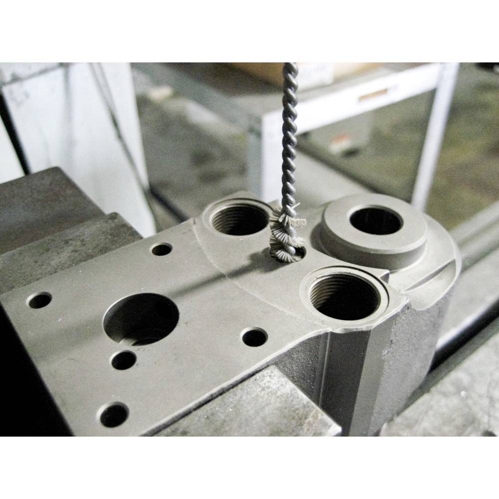 Metalowy element z wieloma otworami w warsztacie. Jeden wiertacz obrabia jeden z otworów.