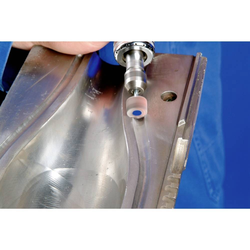 Zbliżenie fragmentu metalowego elementu, który jest obrabiany obrotowym narzędziem szlifierskim. Dłoń trzyma mocno metal.