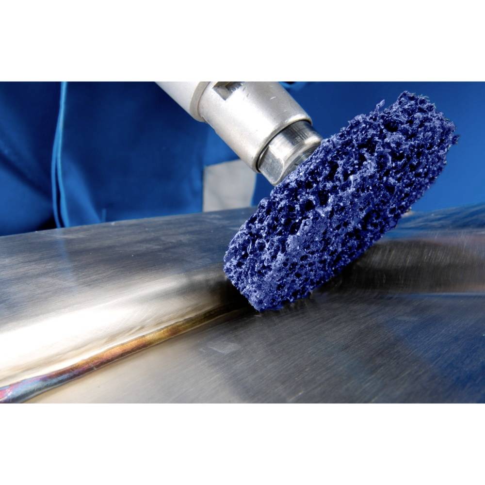 Niebieska szczotka czyszcząca jest prowadzona po metalowej powierzchni. Osoba ubrana w niebieskie ubranie trzyma narzędzie.