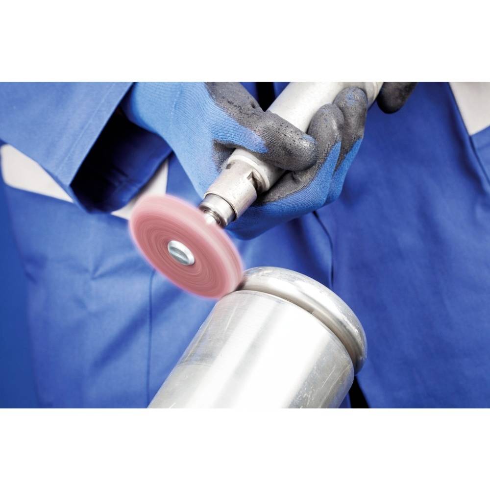 Osoba w niebieskich rękawicach ochronnych poleruje metalową rurę szlifierką. Tło jest rozmyte, fokus skierowany na maszynę.