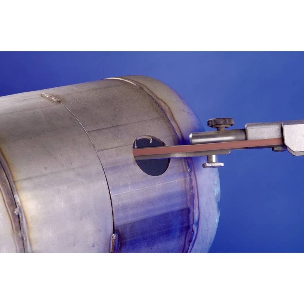 Metalowy cylinder z otworem, przez który rozciąga się przyrząd pomiarowy. Instrument mierzy lub bada cylinder.