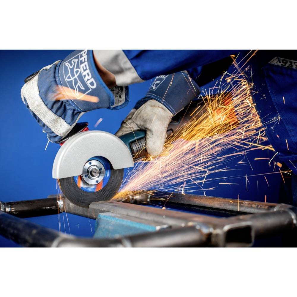 Osoba w odzieży ochronnej używa szlifierki kątowej na metalowej ramie, podczas gdy wokół lecą iskry.