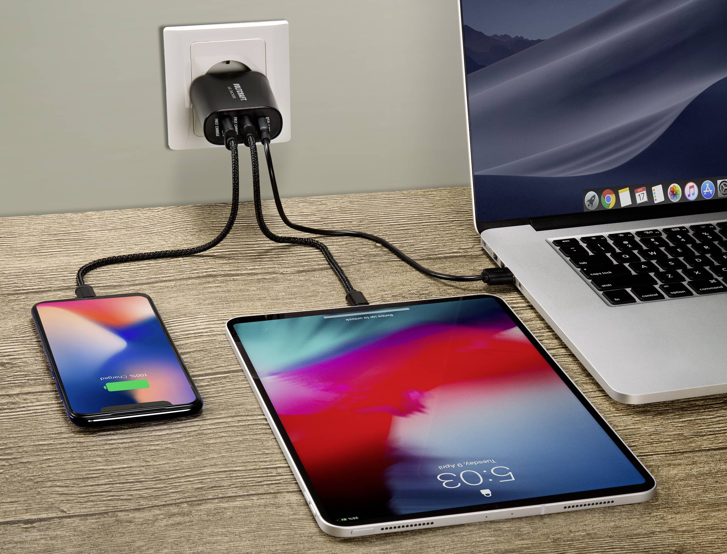 Laptop, tablet i smartfon są podłączone przewodami do ładowarki w jednym gnieździe elektrycznym.