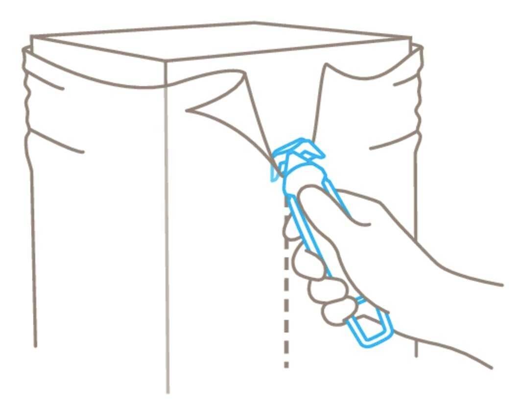 Ręka otwiera zafoliowane opakowanie plastikowym nożem wzdłuż linii przerywanej.