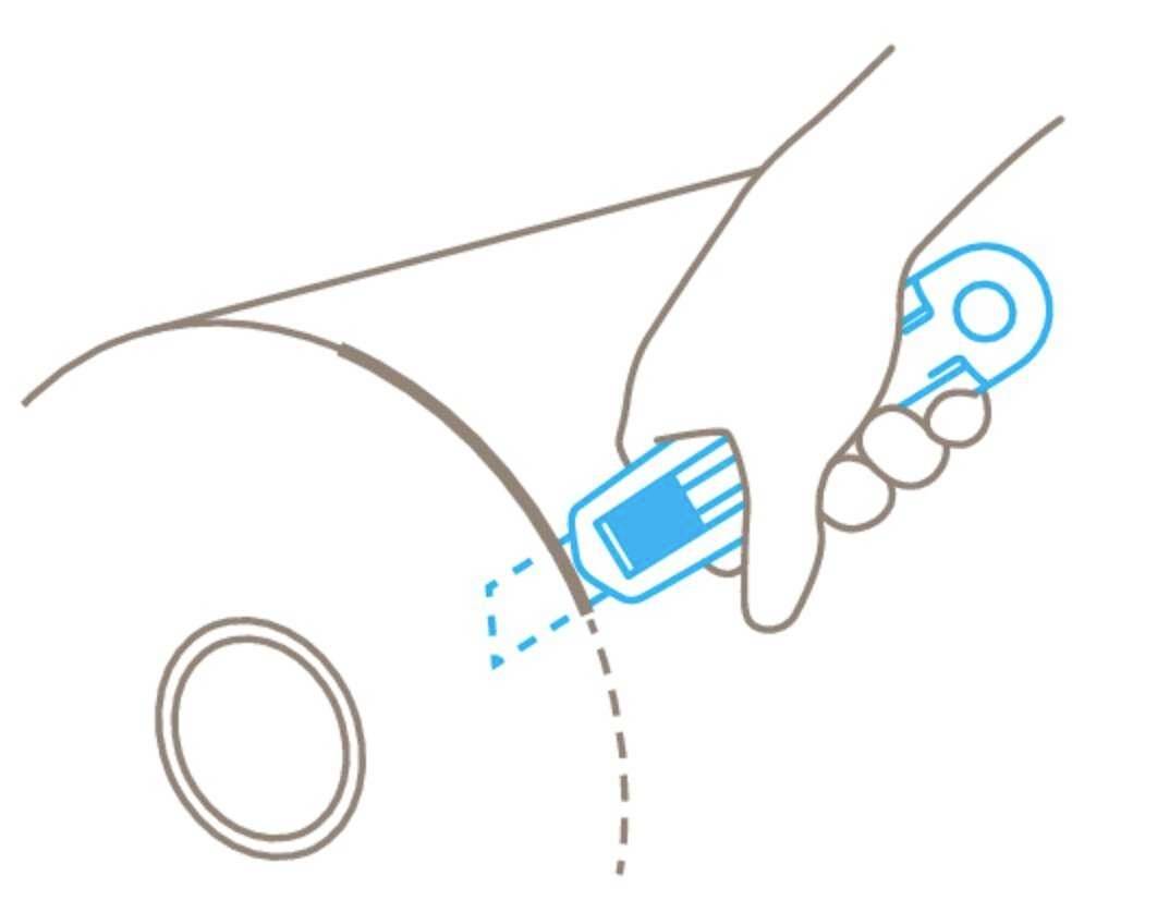 Dłoń trzyma nóż introligatorski i przecina wzdłuż linii przerywistej na rolce materiału opakowaniowego.