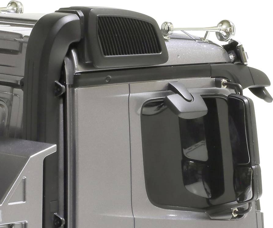 Ilustracja przedstawia kabinę kierowcy srebrnej ciężarówki, widzianą z boku i z góry. Widoczne są lusterka boczne oraz lampy dachowe.