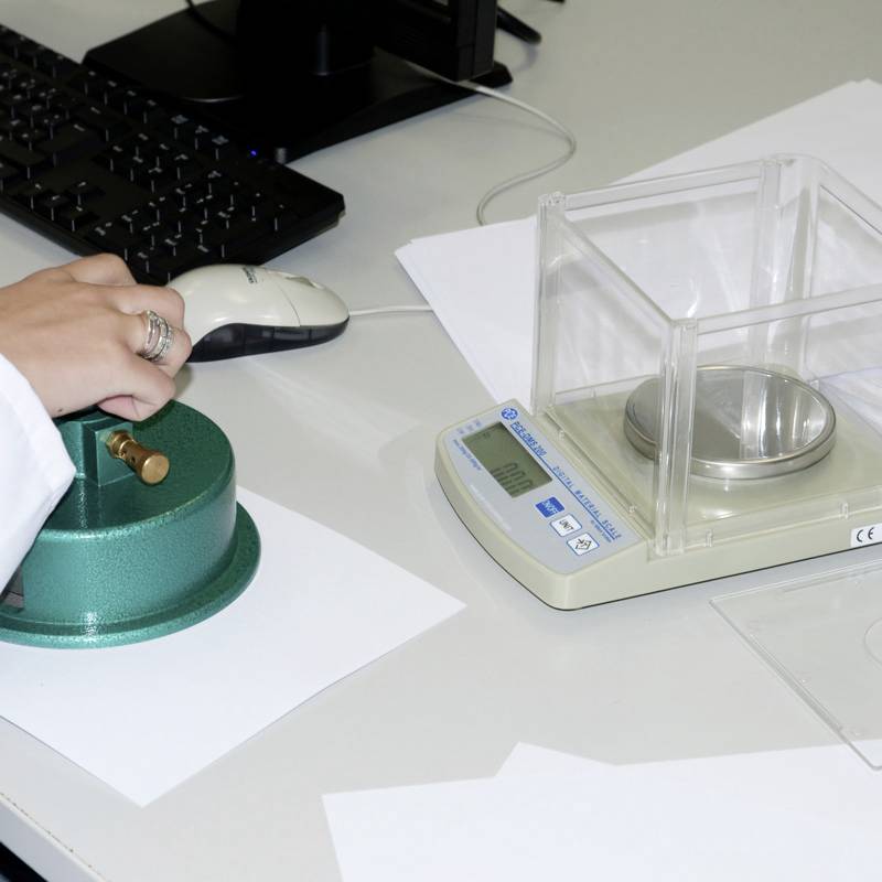 Osoba obsługuje szybką wagę do analizy wilgotności na biurku. Obok leży mysz na podkładce, a w pobliżu widoczna jest klawiatura komputerowa.