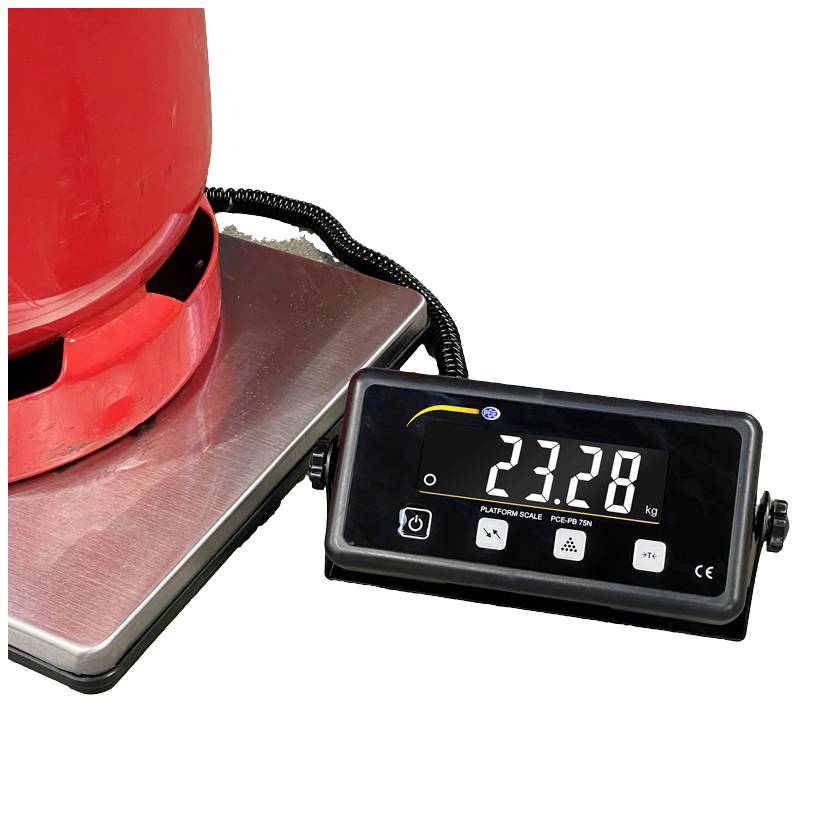 Czerwony cylinder gazowy stoi na wadze platformowej. Wyświetlacz wagi wskazuje wagę 23,28 kg.