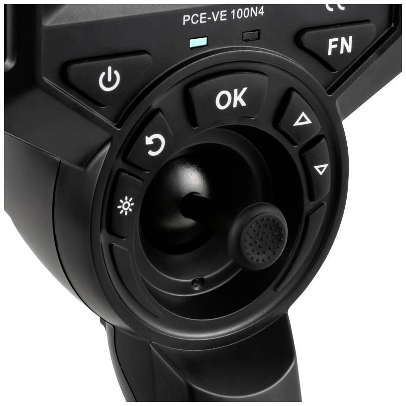 Zbliżenie elementu sterowania z wieloma przyciskami, w centrum którego znajduje się joystick. Przyciski są oznaczone symbolami funkcji i nawigacji.