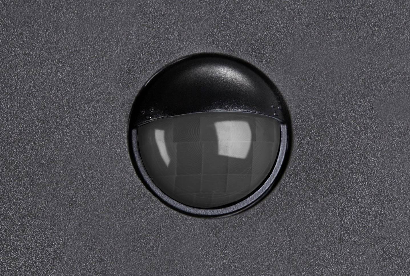 Czarna, półkolistej kształtu kamera monitoringu jest zainstalowana w szarej ścianie, prawdopodobnie w celu nadzoru bezpieczeństwa.