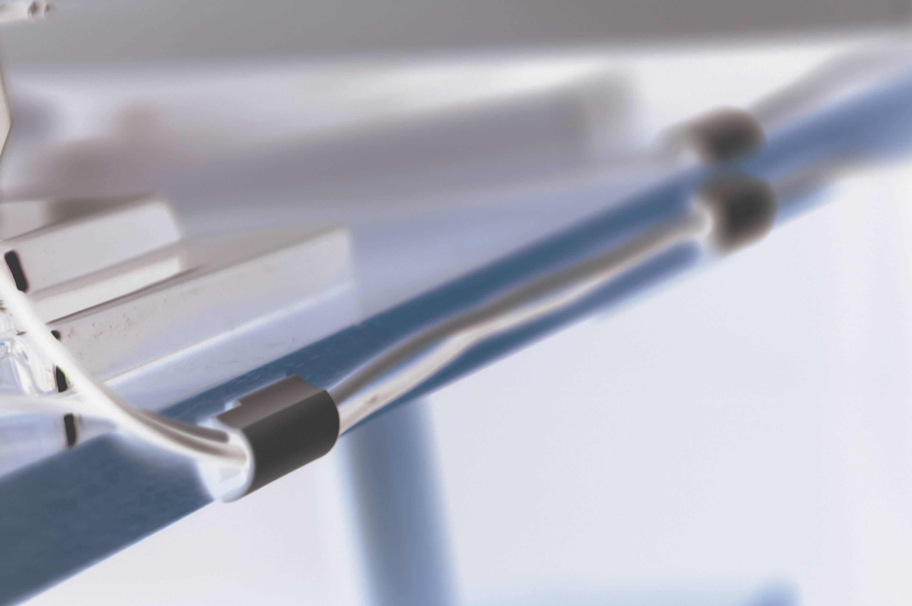 Rozmyty obraz błyszczącego, zakrzywionego obiektu z dwoma czarnymi końcami na niebiesko-białym tle.