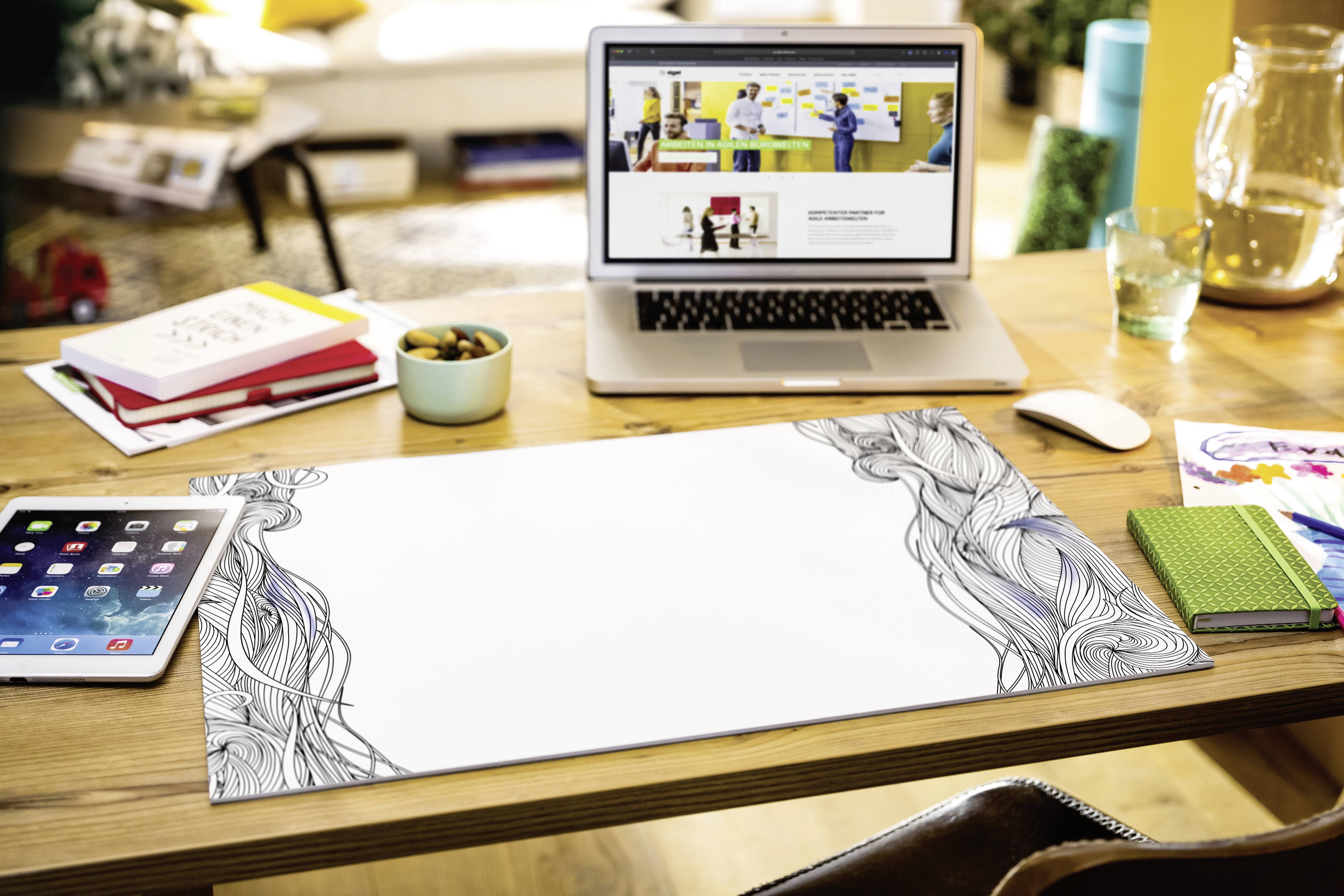 Laptop na biurku wyświetla stronę internetową przedstawiającą ludzi podczas prezentacji. Obok leżą tablet i notatniki.