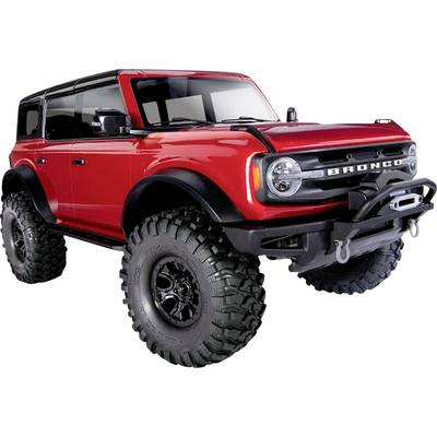 Czerwony samochód terenowy widziany z boku. Duże opony, czarna osłona, solidna budowa. Widok z przodu podkreśla agresywny wygląd w stylu offroad.