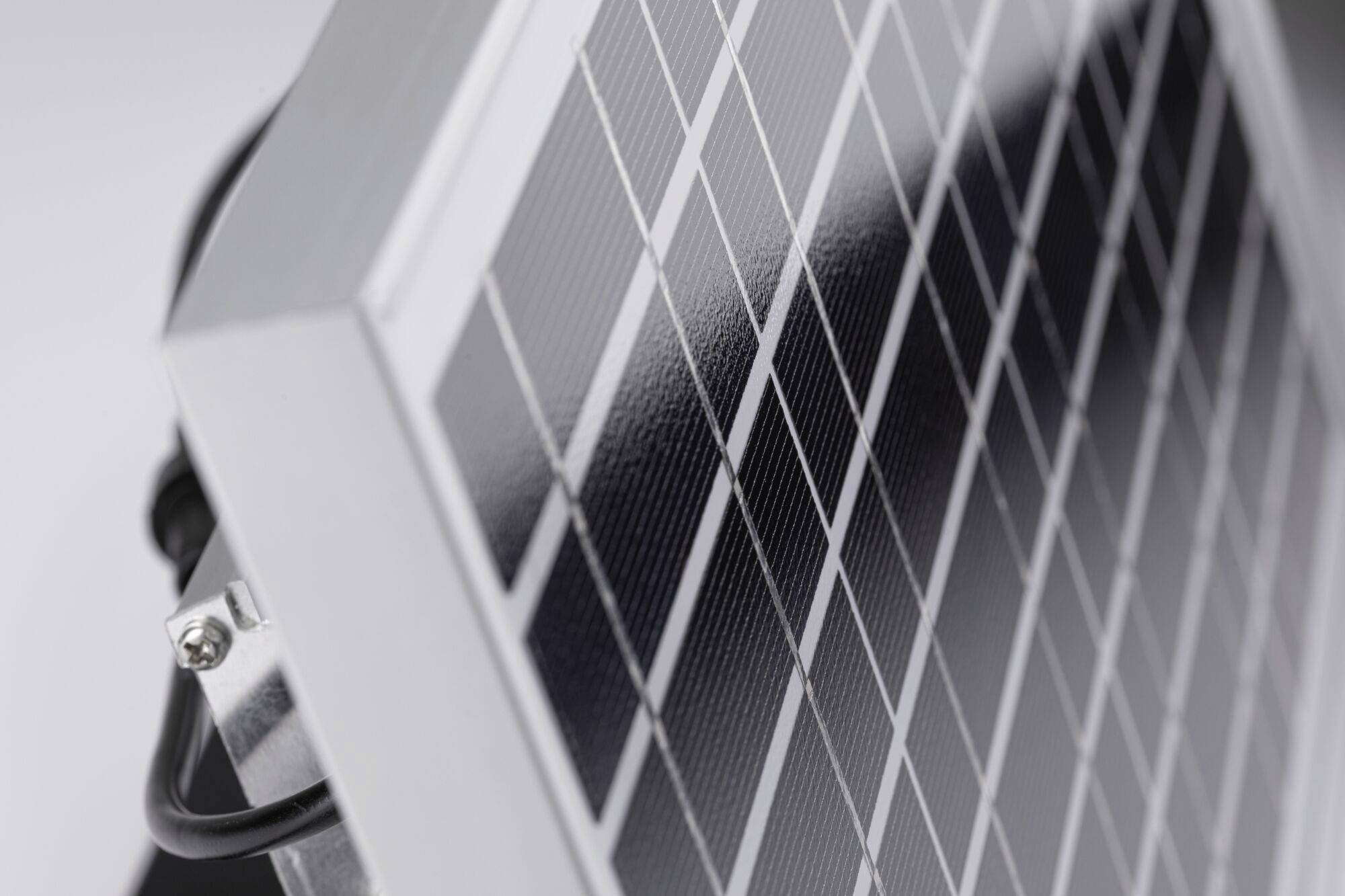 Zbliżenie modułu solarnego z widocznymi panelami. Srebrna ramka i okablowanie są widoczne po lewej stronie.
