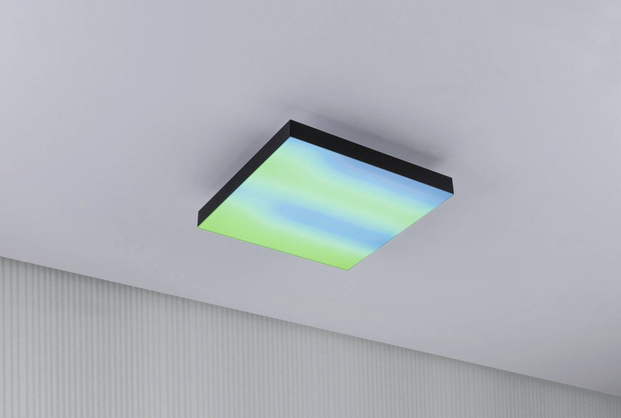 Kwadratowa lampa sufitowa LED o gradiencie barw od niebieskiego do zielonego, zamontowana na białym suficie w nowoczesnym pomieszczeniu.