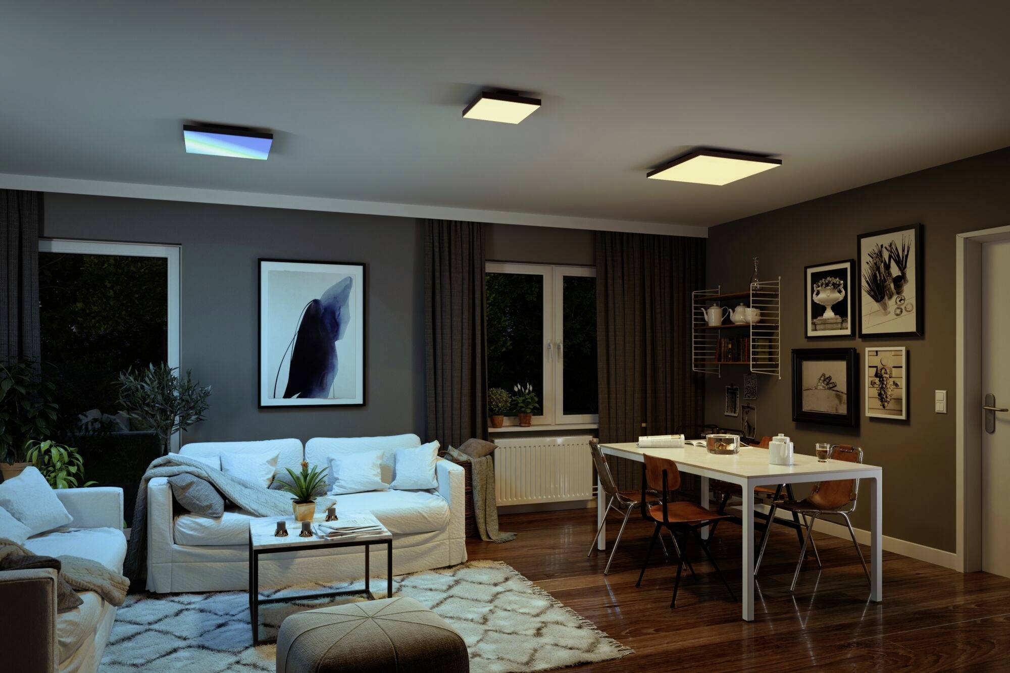 Nowoczesny salon z przytulnym oświetleniem. Kanapa, stolik kawowy i stół jadalniany z krzesłami wypełniają przestrzeń. Na ścianach wiszą obrazy.