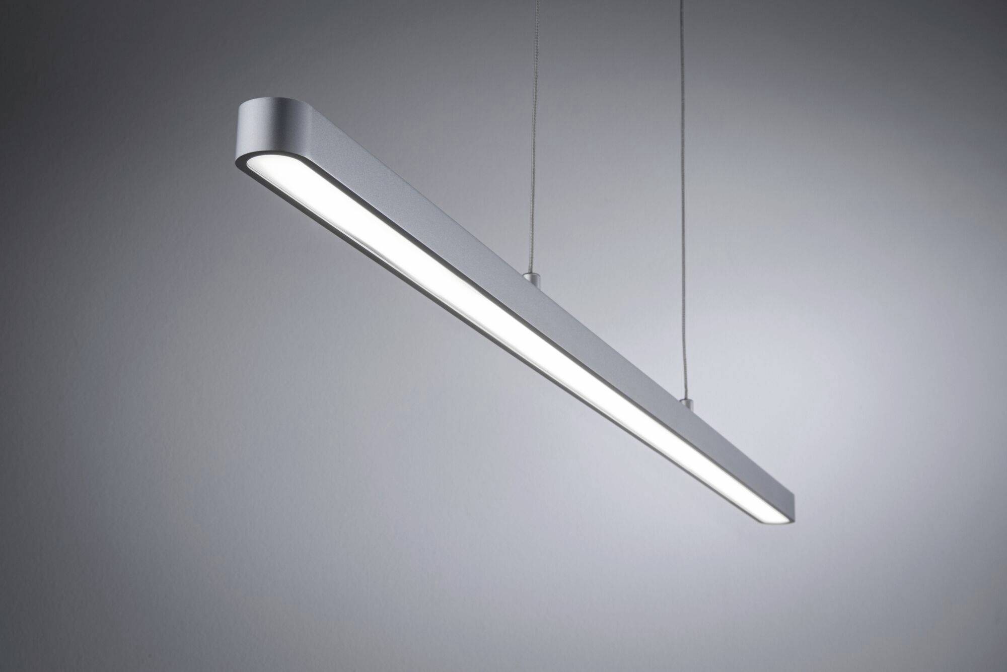 Smukła, wisząca lampa LED o nowoczesnym designie, rzuca ostre światło i zawieszona jest suficie w minimalistycznym wnętrzu.