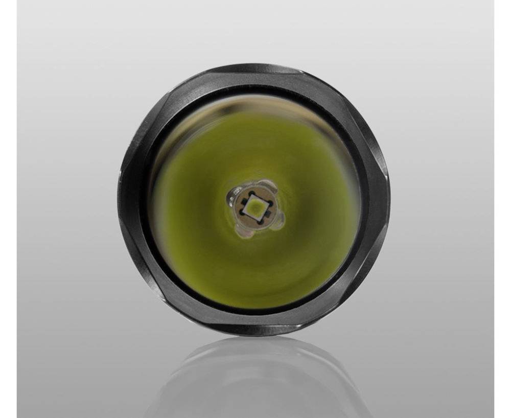 Zbliżenie lampy LED z okrągłą metalową obudową i soczewką centralną, na szarym tle.