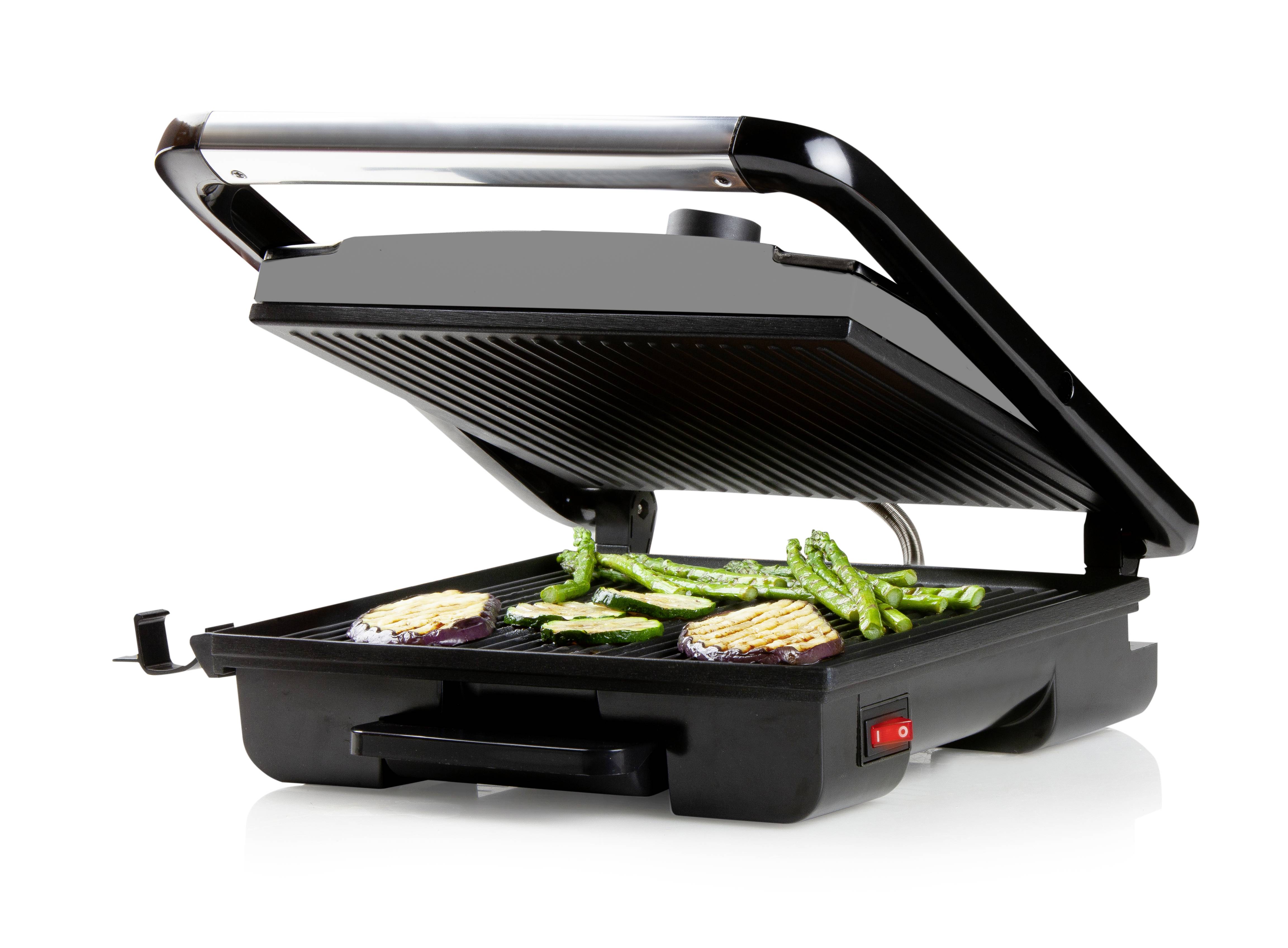 Elektryczny grill z otwartą pokrywą. Na powierzchni grilla leżą różne kawałki warzyw, w tym szparagi i bakłażany.