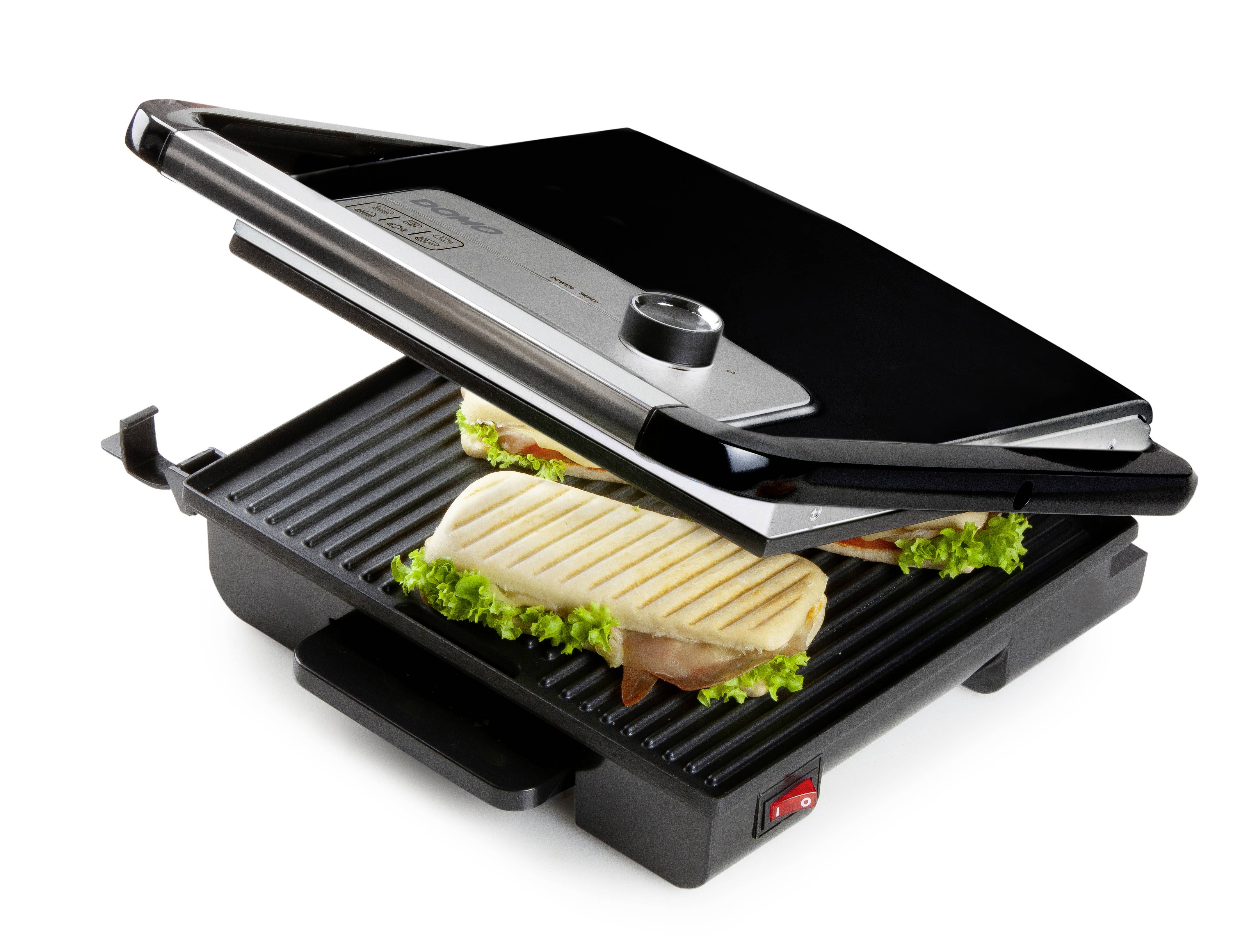 Otwarty grill kontaktowy z dwoma kanapkami, pod którymi znajdują się liście sałaty i szynka. Grill posiada regulację temperatury.