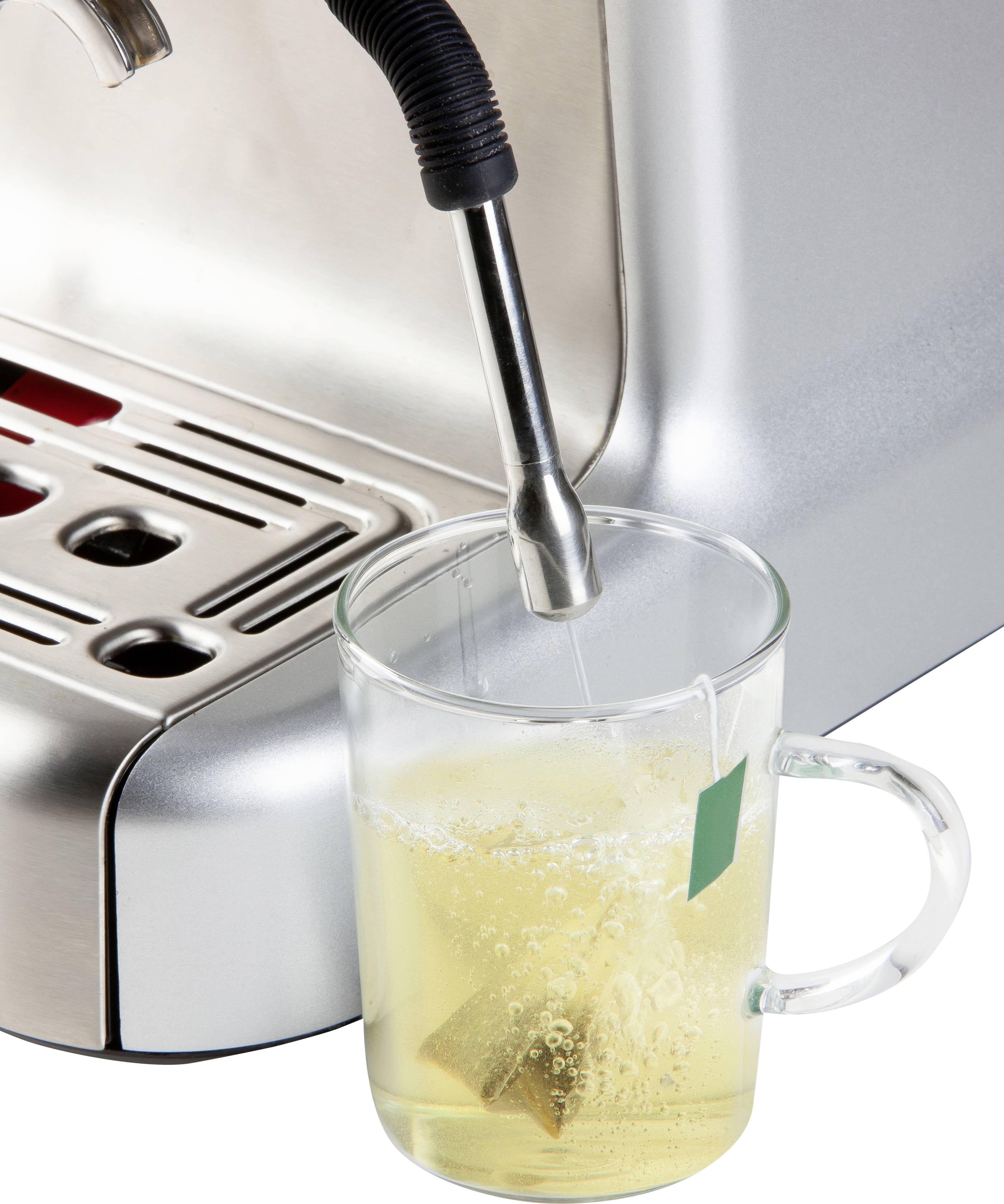 Filiżanka z torebką herbaty jest napełniana gorącą wodą z ekspresu do kawy.