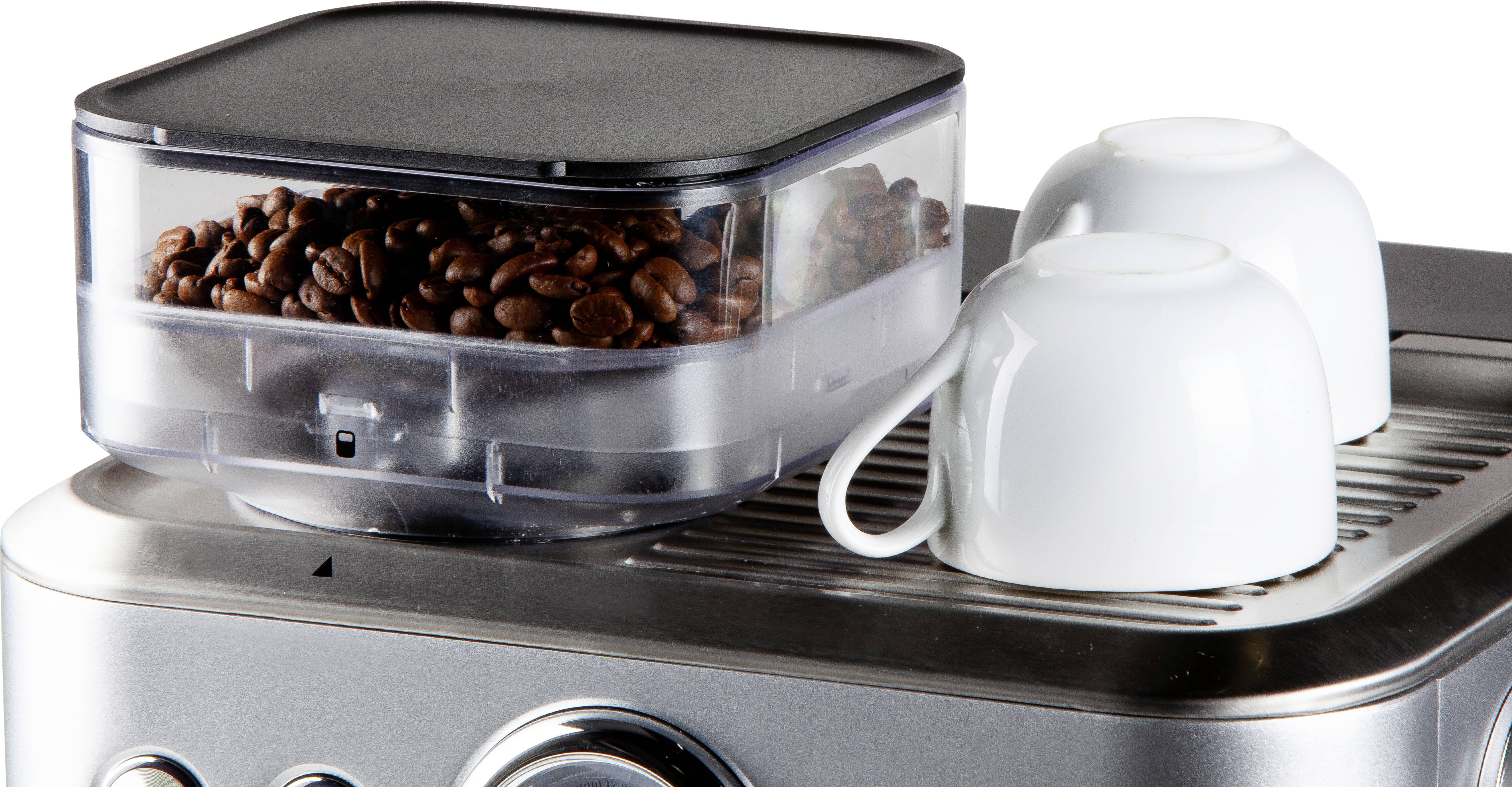 Ekspres do kawy z ziarnami kawy w pojemniku oraz dwiema pustymi białymi filiżankami na obudowie.