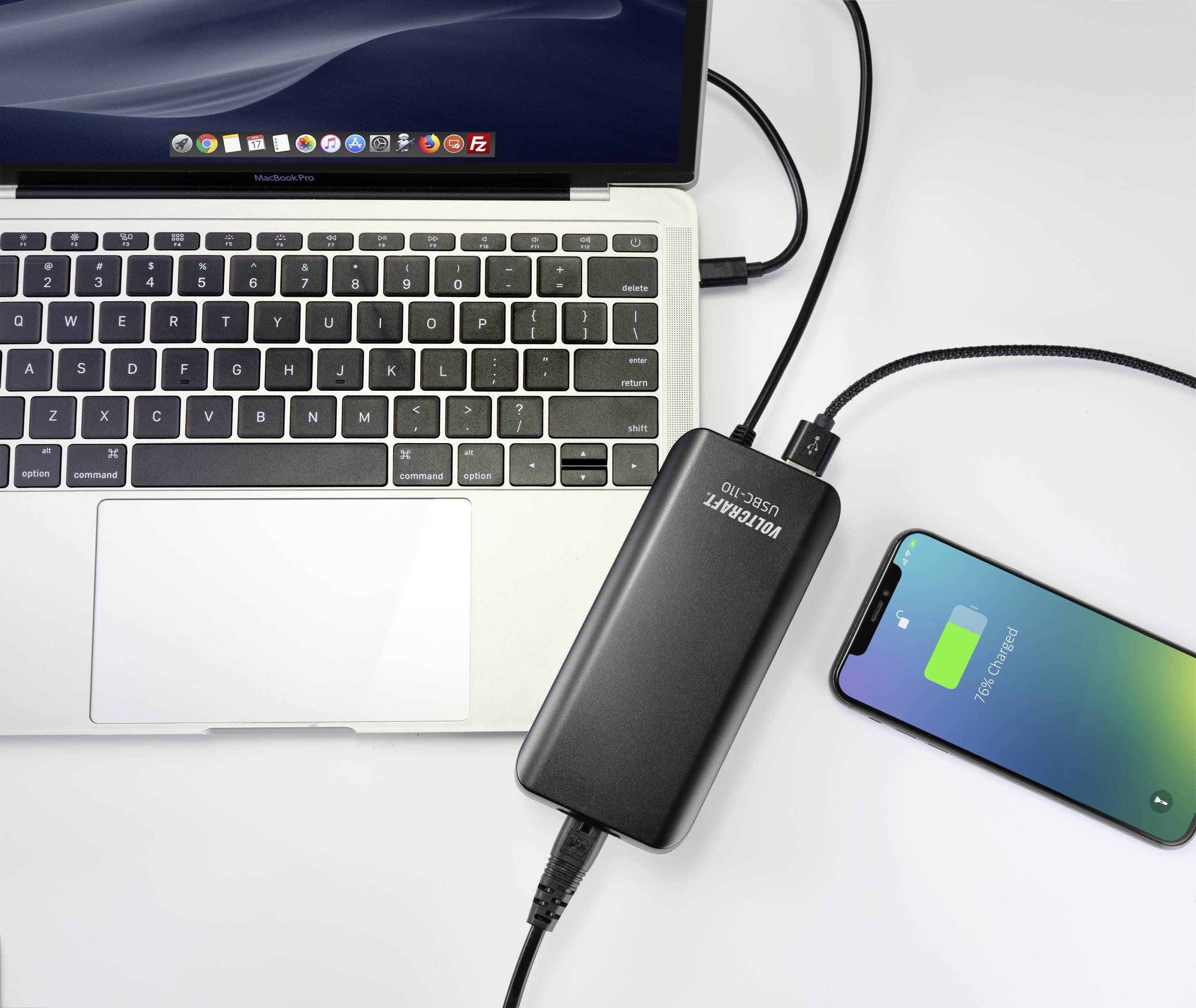 Laptop i smartfon, oba ładowane za pomocą powerbanku. Laptop jest otwarty, na ekranie smartfona widać napis 'Charging'.