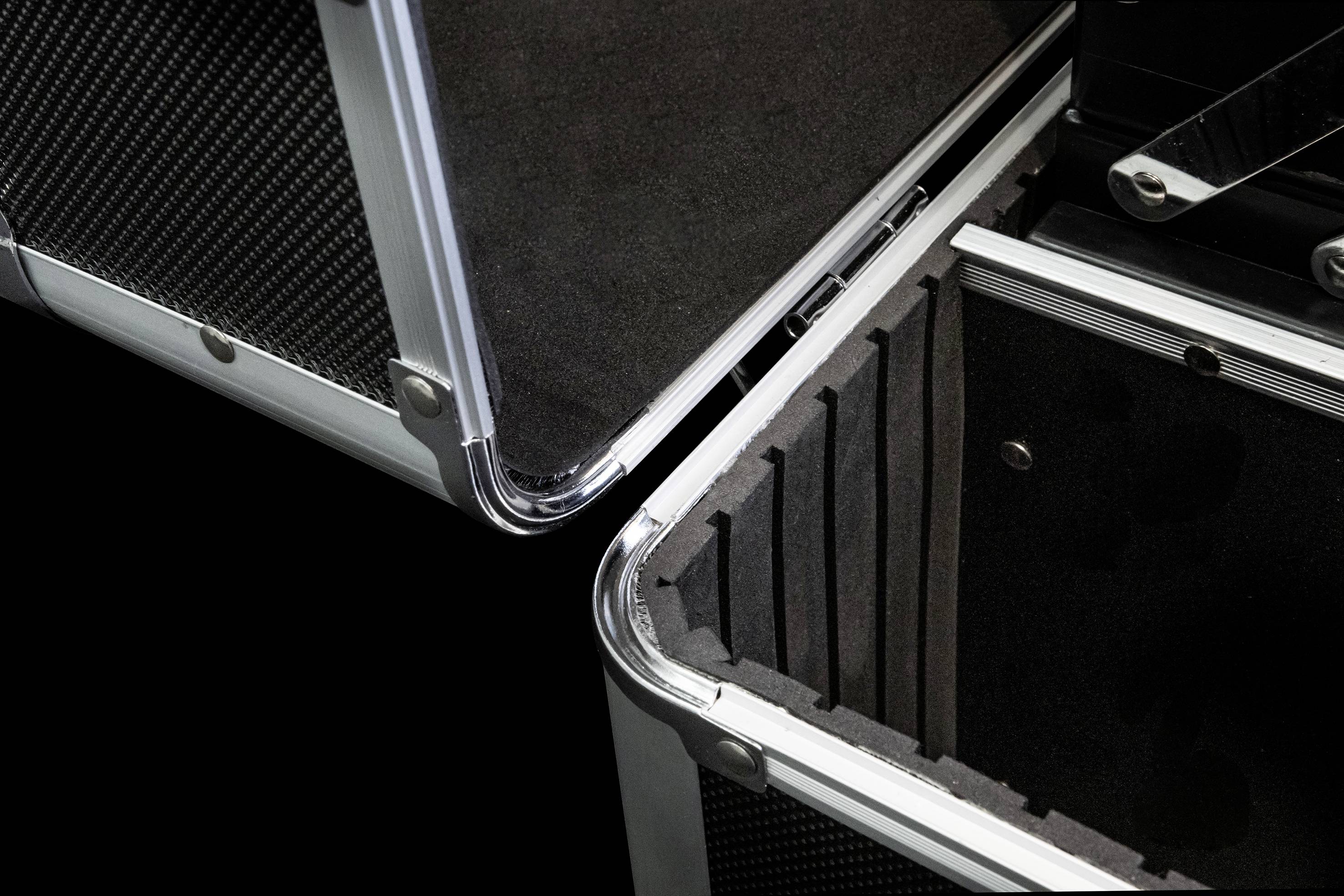 Otwarty, pusty aluminiowy kufer z wewnętrznym wyściełaniem ochronnym, odpowiedni do bezpiecznego przewozu delikatnych przedmiotów.