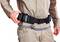 Osoba w odzieży roboczej nosi pas narzędziowy z wieloma kieszeniami. Ręka reguluje pas.