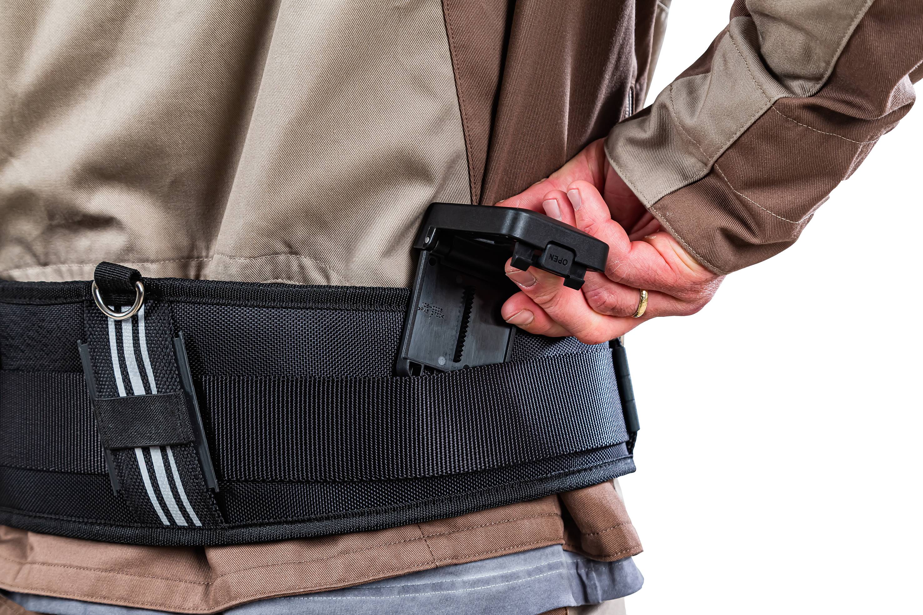 Osoba wkłada magazynek do brązowego pasa z czarnym uchwytem.