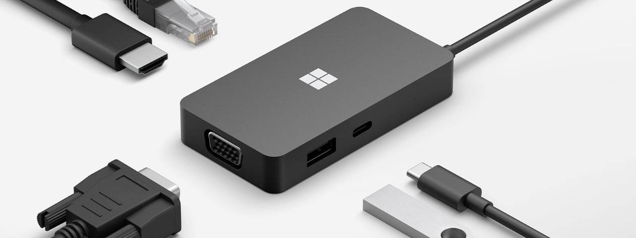 Czarny adapter z wieloma wejściami kablowymi, w tym HDMI, VGA, USB-C i Ethernet, na białym tle.