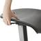 Jedna ręka reguluje siedzisko czarnego fotela biurowego. Fotel posiada regulację wysokości i ergonomiczny kształt.