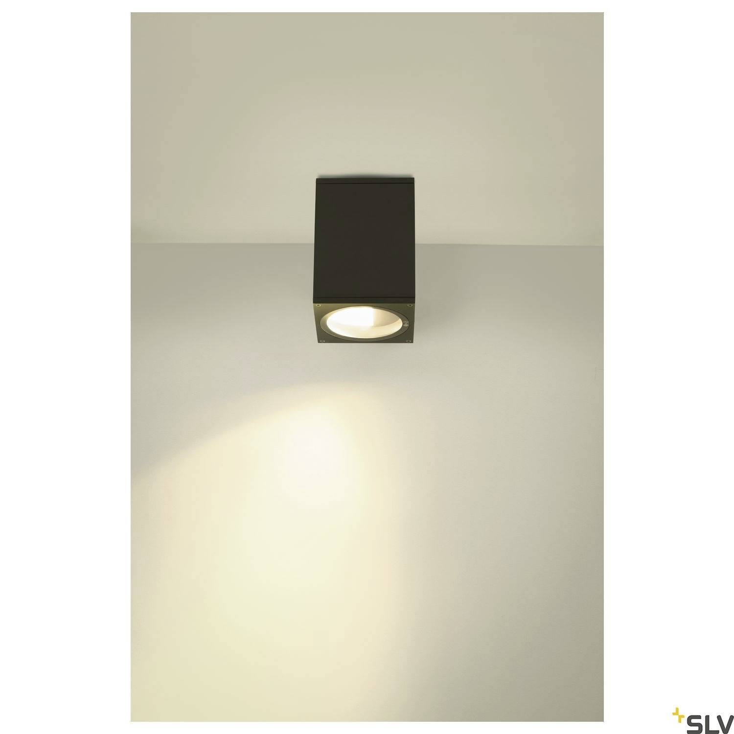Nowoczesna lampa ścienna z kwadratową obudową, która świeci w dół i w kierunku ściany, tworzy ciepłą poświatę.