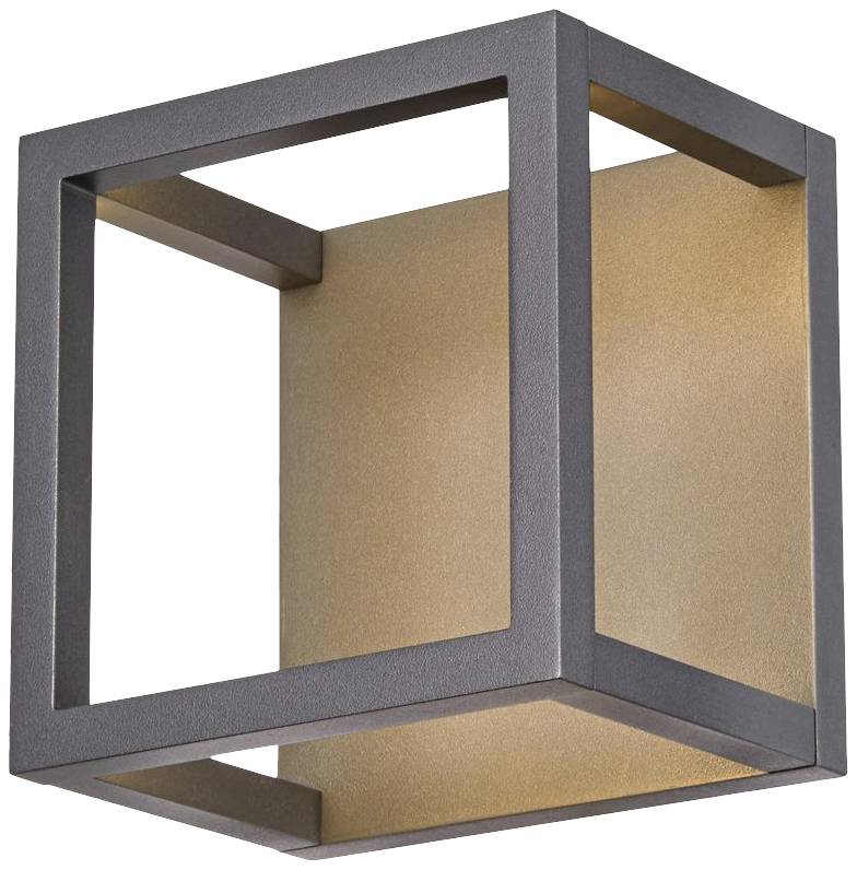 Nowoczesny kinkiet w kształcie otwartego sześcianu z czarną ramą i złotym wnętrzem, emitujący rozproszone światło.