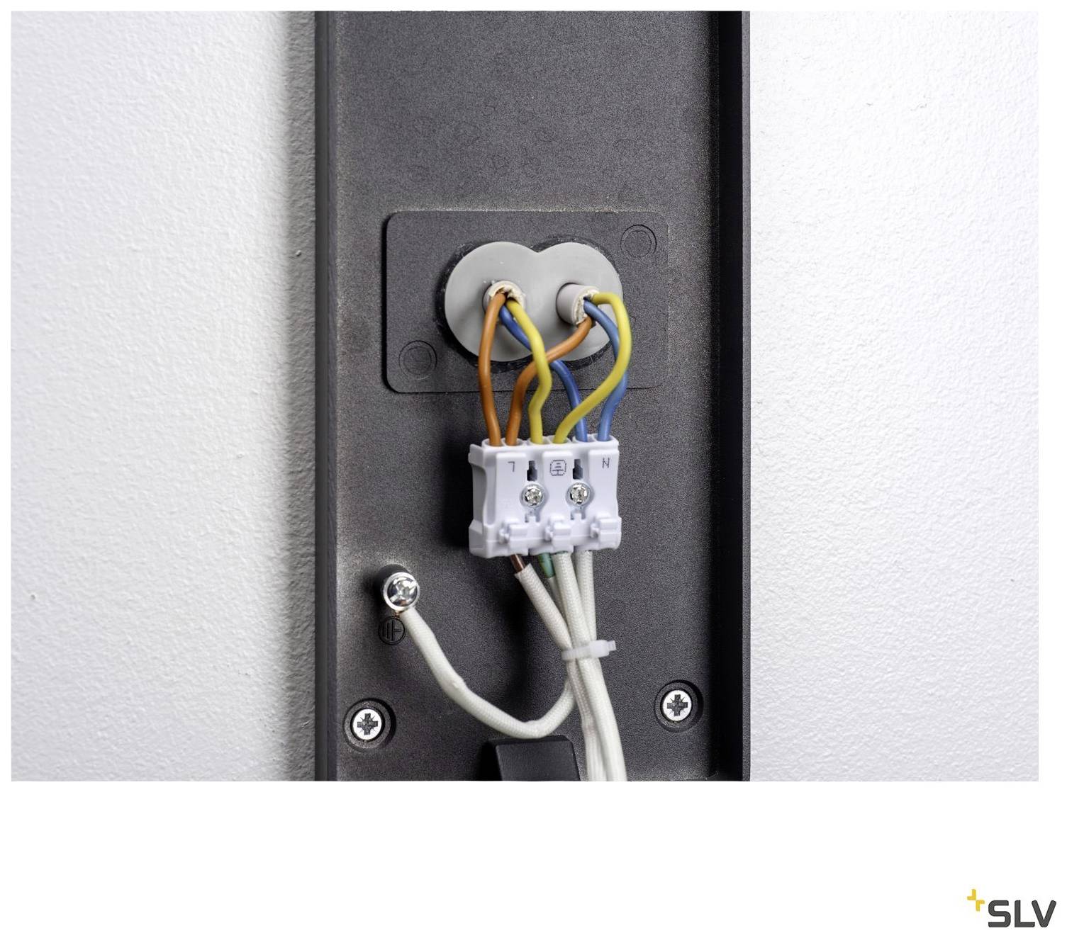 Uchwyt ścienny z widocznym okablowaniem: Trzy kolorowe przewody (pomarańczowy, niebieski, brązowy) są podłączone do białego bloku zacisków przyłączeniowych.