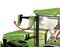 Zielony traktor z bocznym lusterkiem, które jest pokazane jako uniesione do góry za pomocą dwóch czerwonych strzałek.