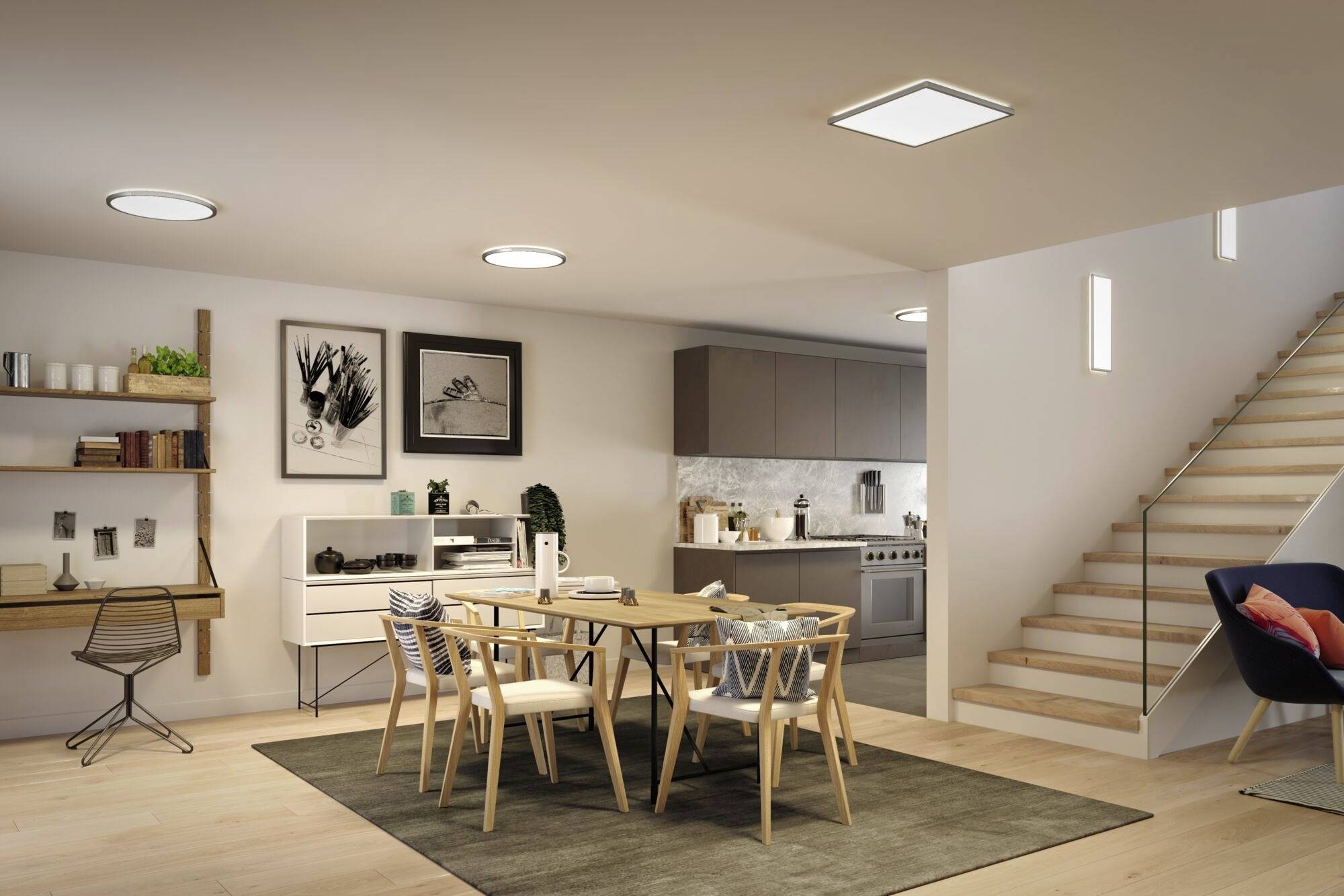 Jadalnia w nowoczesnym stylu z drewnianymi krzesłami wokół szklanego stołu, z otwartą kuchnią w tle i schodami po prawej stronie. Jasne oświetlenie.