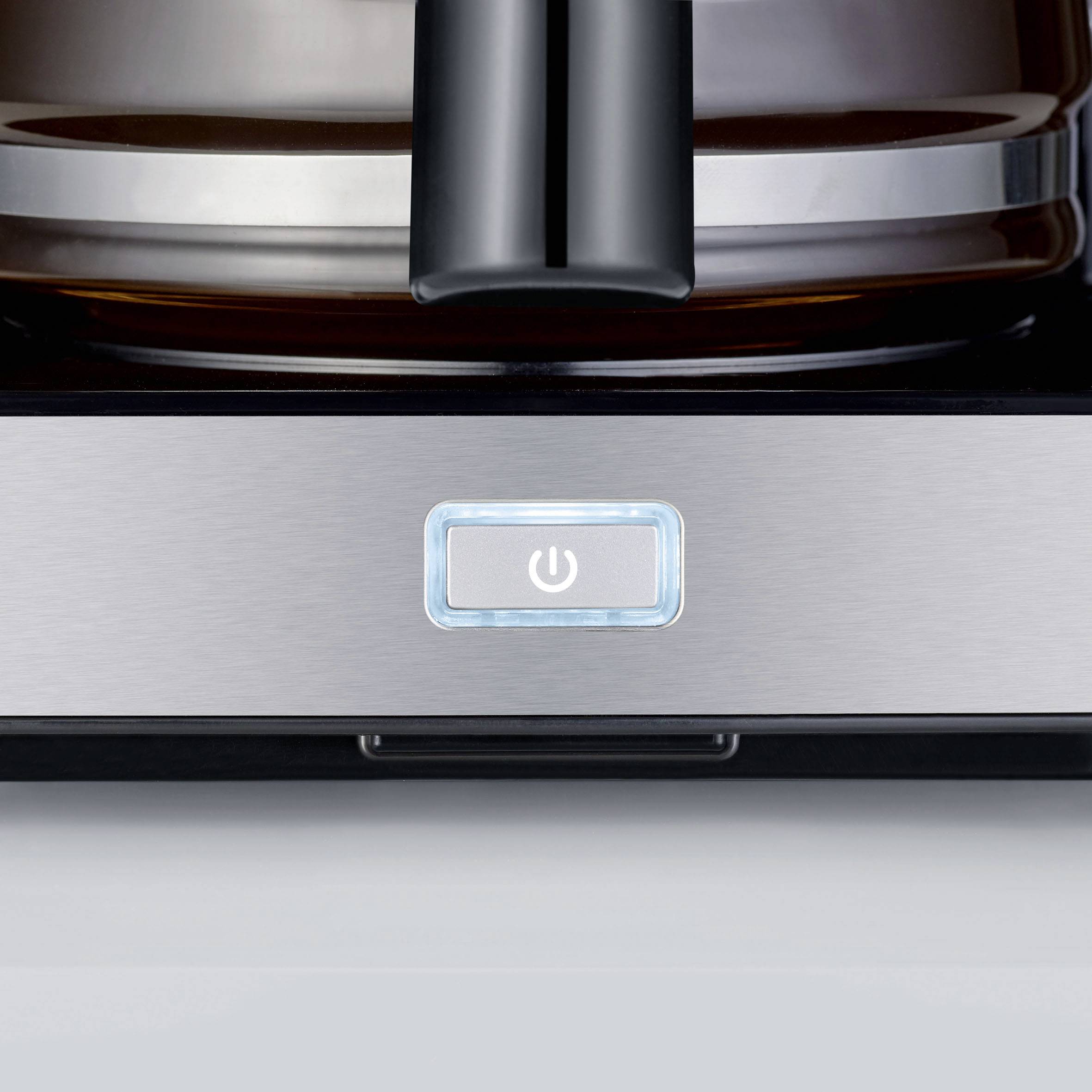 Ekspres do kawy z podświetlanym przełącznikiem włączania/wyłączania na srebrnej obudowie; kadry ukazują dzbanek w tle.