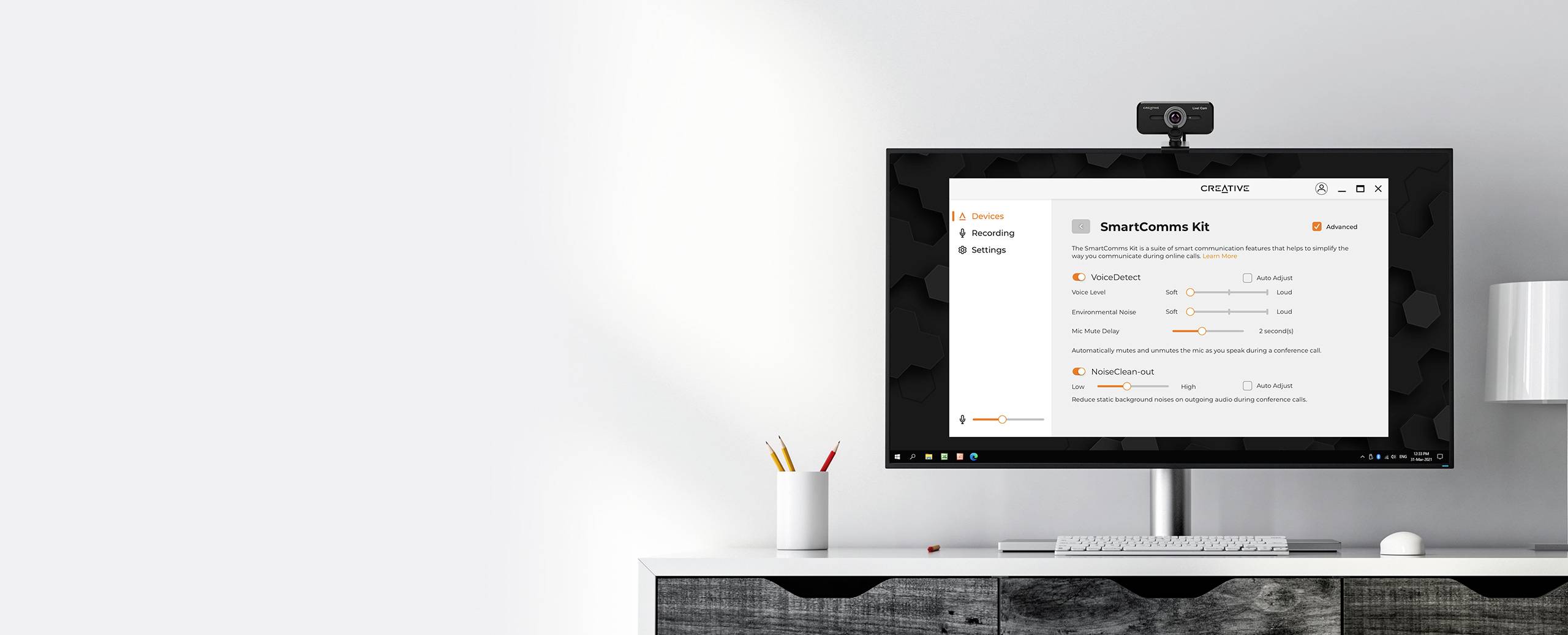 Monitor na biurku wyświetla oprogramowanie z ustawieniami. Kamera internetowa u góry monitora. Kubek z długopisami po prawej stronie.