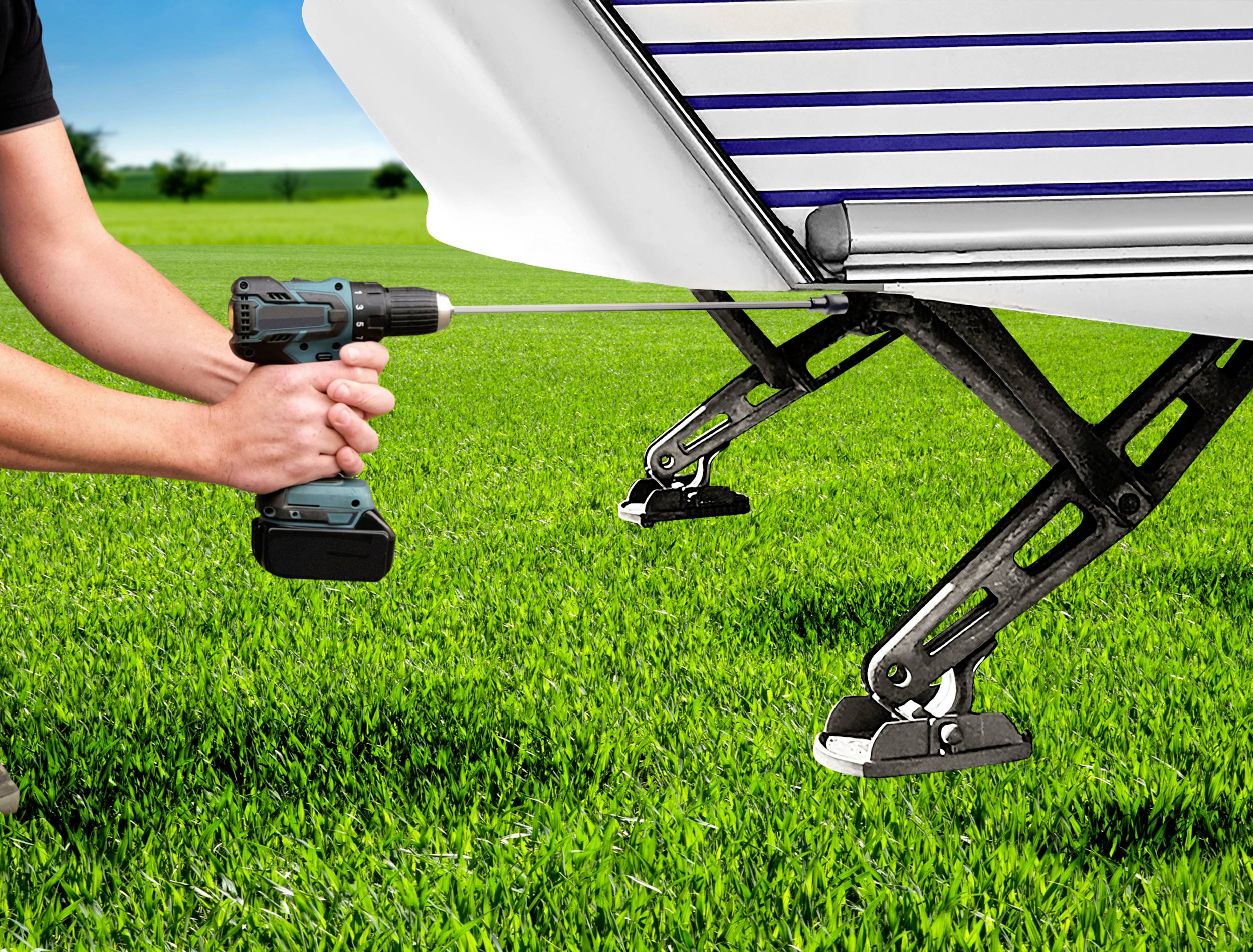 Osoba używa wiertarki elektrycznej do wyregulowania podpór przyczepy kampingowej na zielonej łące.